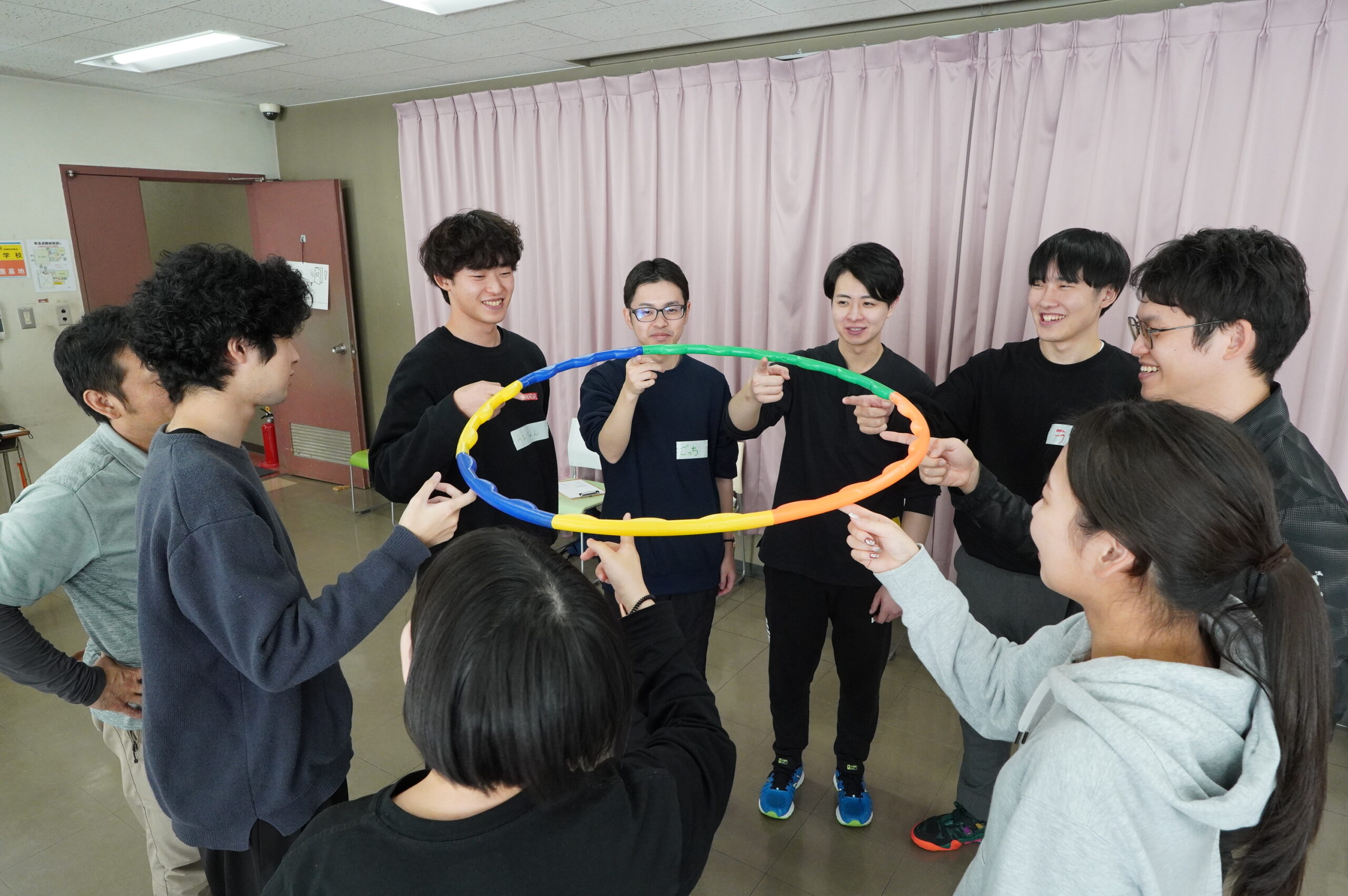 2025.11.14 入社3年目アクテビティ研修2。フラフープをみんなの指1本で支えます。集中力とチームワークが必要なヘリウムリングゲームに挑戦！
